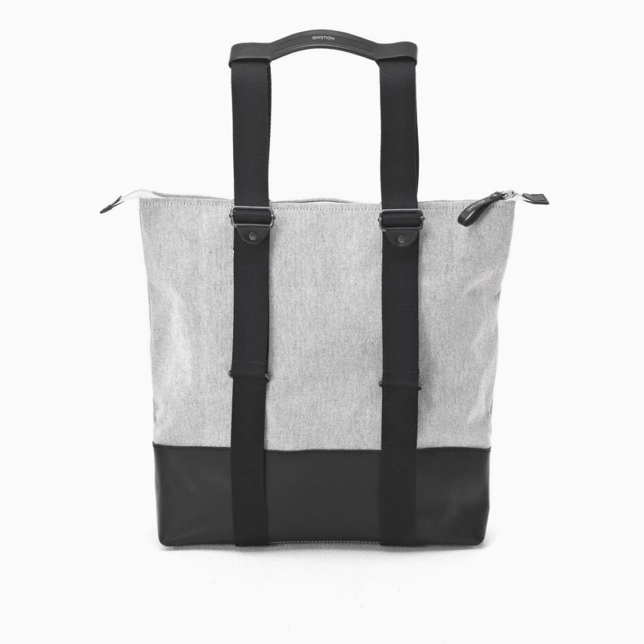 Front of tote bag with washed black canvas body, black straps, and tan leather handles and accents.